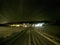 Long snowy farm road at midnight with houses