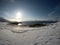 Long snowy field with footprints with beautiful bay, blue fjord and sky on a sunny winter day