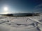 Long snowy field with footprints with beautiful bay, blue fjord and sky on a sunny winter day