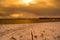 Long snowy sea shore in the arctic circle wintertime during golden sunset over snowy mountain peaks