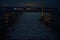 Long snowy wooden pier at night with mountain and fjord