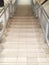 A long staircase upstairs with steps of stone tiles. Iron railings are light gray colored steel pipes.