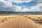 Long straight dirt road in Utah with dramatic clouds