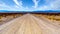 A long and straight gravel road in the semi desert landscape near Crystal Springs and Area 51 in the desolate land of Nevada