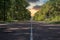 Long straight road going through the abandoned chernobyl exclusion zone. Endless road leading into a golden late afternoon