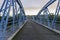 Long straight road between steel arches of bridge leading to distant misty hills at Millers Flat South Island New Zealand