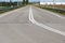 Long straight tarmac road with open fields, disappearing over far horizon