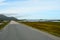 Long strait road with ocean water on sides and mighty mountains in summer