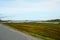 Long strait road with ocean water on sides and mighty mountains in summer