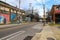 A long street with tall telephone poles and colorful wall murals and bare winter trees and tall curved light posts with blue sky