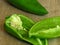 Long sweet green pepper cut in half on rustic style wood background. Pepper seeds.