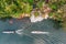 Long tail boat dragging wooden raft near waterfall flowing in river kwai