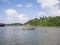 A long tail boat sailed in the middle of the sea passing through an island that has temples