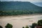 A long-tailed boat with full passengers is running upstream against the river tide along muddy of Mekong river at Amphoe Khong Ch