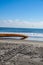 Long thick rusty pipe running along wet beach sand and entering the ground at the edge of the ocean