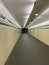 A long tunnel looking towards a distant doorway lined by yellow and green tiles