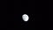Long video of close up wanning gibbous grey colored moon moving across totally black sky from left to right, appears at left side