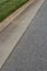 Long view of street, asphalt beside formed concrete curb and grass