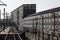 Long view of train tracks alongside expansive warehouses of brick with walls of windows, industrial complex