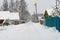 Long village road covered with snow, snow on trees, houses in the village, power pole in winter