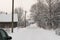 Long village road covered with snow, snow on trees, houses in the village, power pole in winter