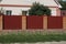 long wall of a fence of red iron and brown bricks