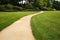 Long white curved garden path surrounded by lush foliage