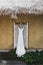 Long white wedding dress hanging outside on traditional bali house