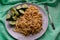 Long and wide pasta spaghetti noodles under viscous melted cheese on a platter with sliced â€‹â€‹fresh cucumbers on a bright green