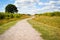 Long winding gravel footpath through a country field No people. view to horizon