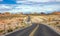 Long winding highway with ups and downs, cloudy blue sky. Valley of Fire Nevada, USA