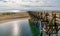 Long wooden boardwalk pier leads from one beach to another over a small ocean inlet