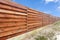 Long wooden cedar fence against blue sky.