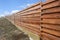 Long wooden cedar fence against blue sky.