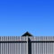 Long wooden cedar fenceA long grey fence against a blue sky in clear Sunny weather, the roof of the house shows isolation, lonelin