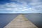 Long Wooden construction jetty at the lake with Dutch cloudy skies