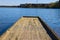 A long wooden dock on the lake with vast blue lake water with lush green and autumn colored trees and plants at Lake Horton Park