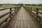 Long wooden pedestrian bridge with railings across the river. background of village, srlective focus