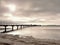 Long wooden pier at coast, cold morning, peaceful silent day