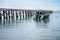 The long wooden pier with light cloud sky, the speed boat, before the sunset