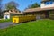 A long yellow empty dumpster seen in the driveway in front of a home being renovated