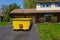 A long yellow empty dumpster seen in the driveway in front of a home being renovated