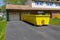 A long yellow empty dumpster seen in the driveway in front of a home being renovated