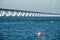 Long Zeeland Bridge, deep blue water with a red buoy, wind turbine in the background.