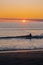 Longboard surfing. Woman surfing during amazing sunset. Midnight sun in Lofoten Islands, arctic surfing