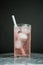 Longdrink glass with white straw in rose colored cocktai