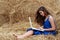 Longer-haired girl sitting on hay with laptop