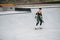 Longshot of a woman skater riding on her board on quarter pipe circle