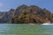 Longtailed speed boats passing a large limestone island in Phang Nga Bay in Thailand