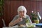 Lonley solitary elderly woman having lunch alone sitting at the table at home. Lonely late life period of a widow.